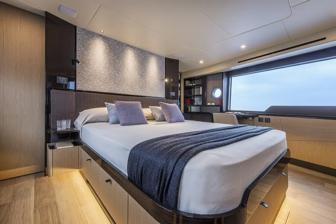 Luxurious yacht interior featuring a double bed with two cushions, stylish decor, and a large window with a sea view.